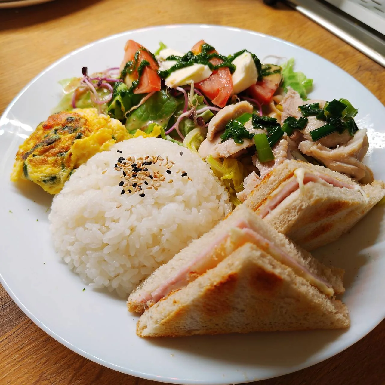 Ein wechselnder Mittagsteller mit Reis, Omelett, Hähnchen, Salat und warmem Sandwich