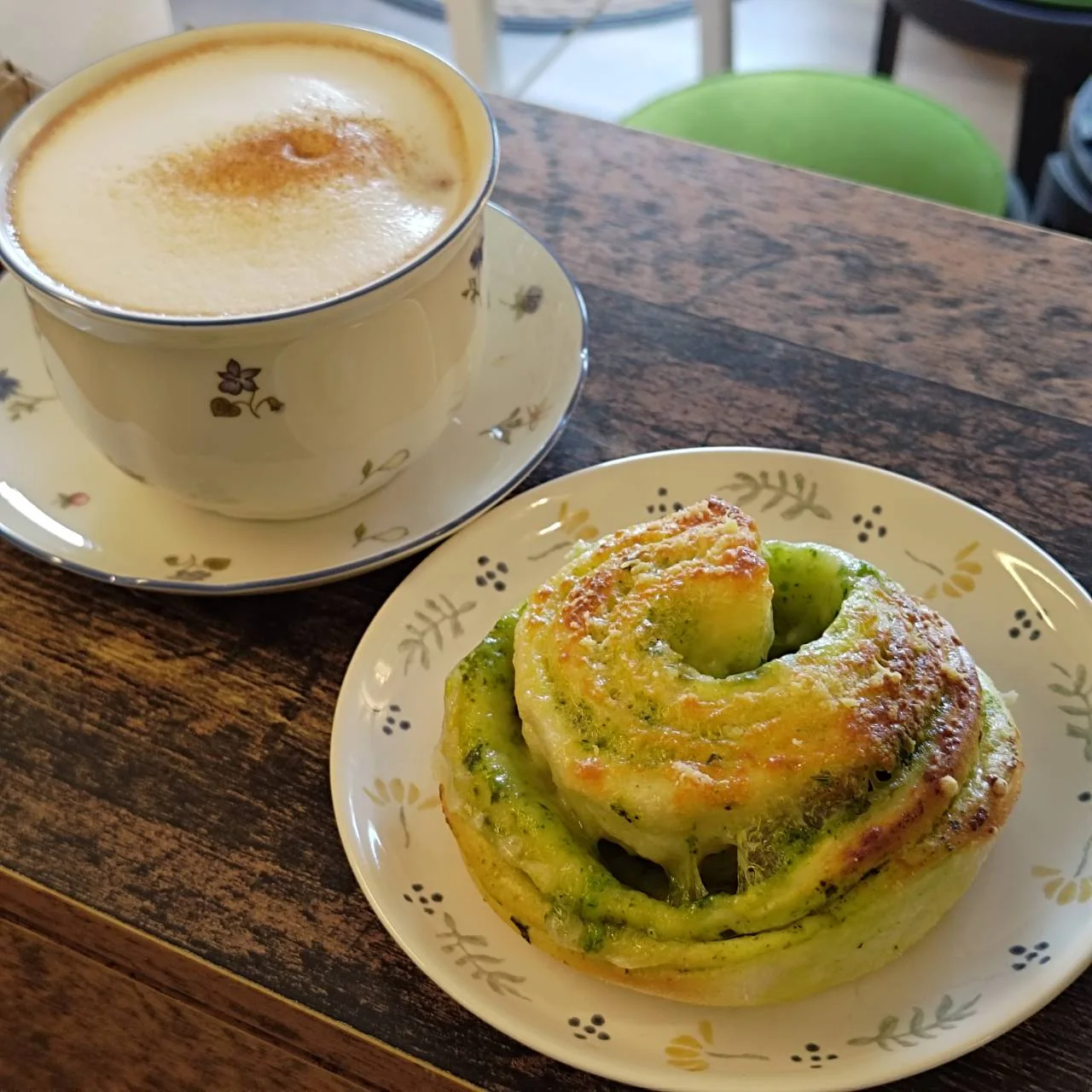 Eine Tasse Kaffee und ein warmes grünes Gebäck auf einem kleinen Tisch im NichiNichi Café