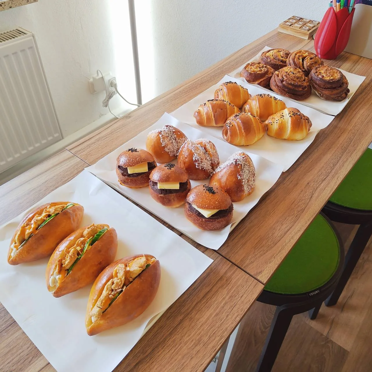 Eine lange kleine Cafétafel mit herzhaften Brötchen, gefüllten Broten und süßem Gebäck