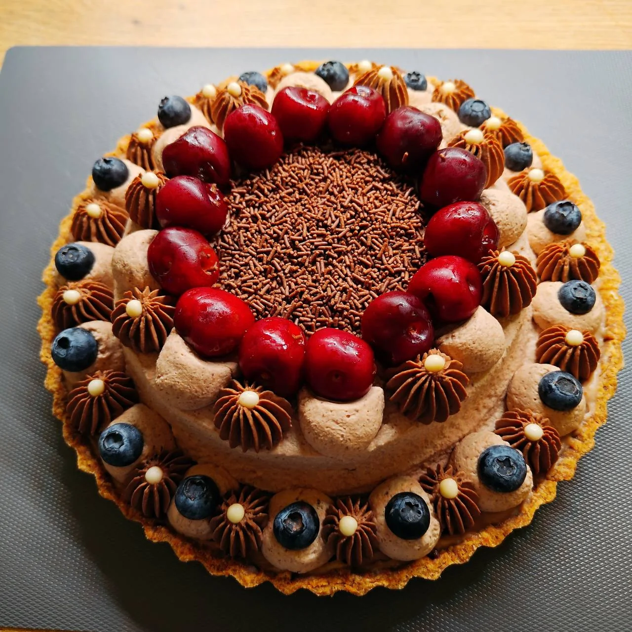 Eine große Schokoladen-Kirsch-Tarte mit frischen Kirschen, Blaubeeren und Schokoladencreme